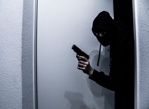 man with a gun opening a door